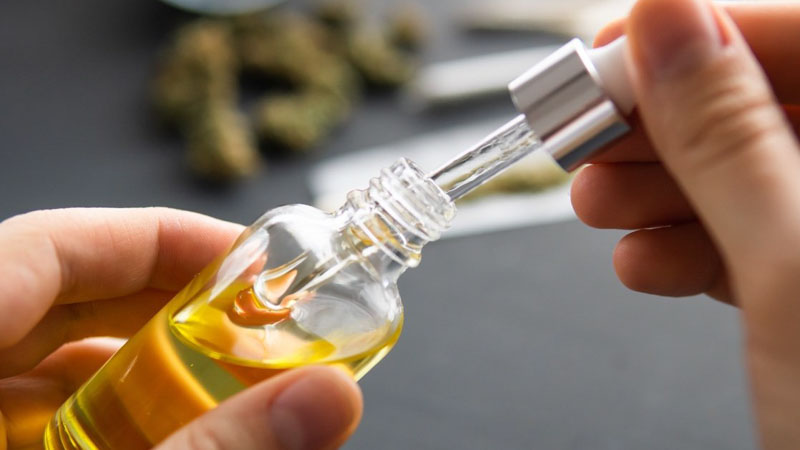 CBD oil from a glass dropper on a persons hands