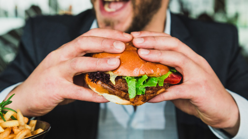 a man holding a hamburger with both hands smiling