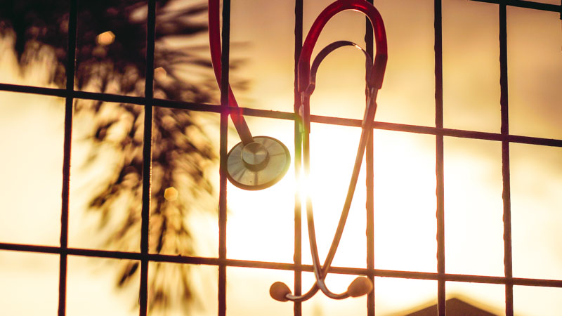 A red stethoscope hanging on a fence 