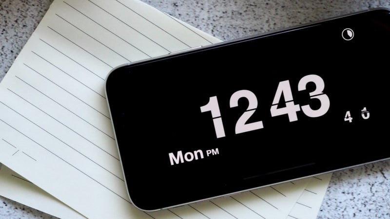 Black iphone display the time on top of a note piece of paper