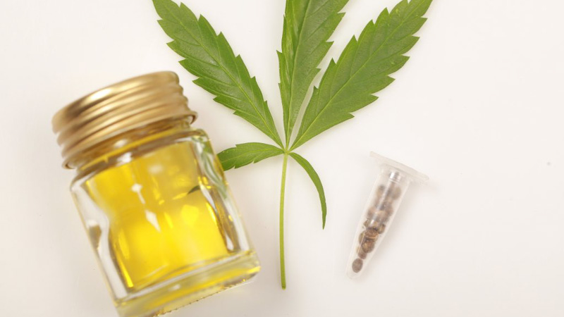 Hemp leaf and oil extract on a white table