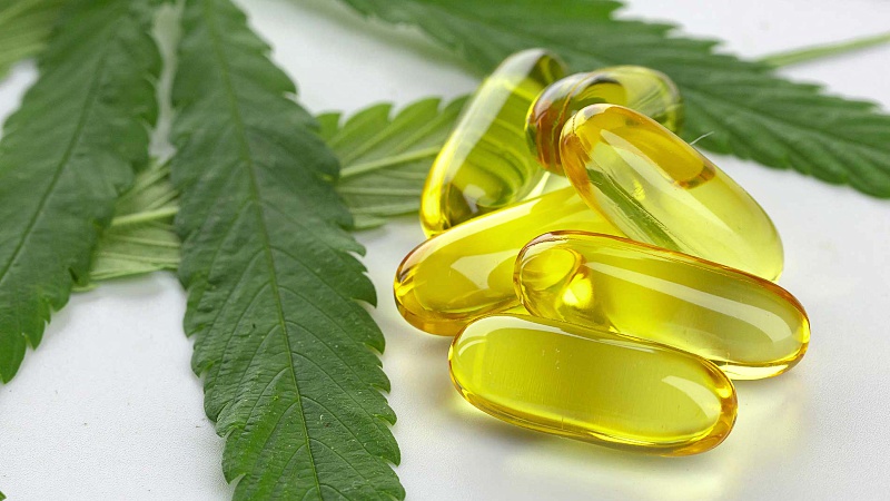 Cannabis capsules with leaves on a white background