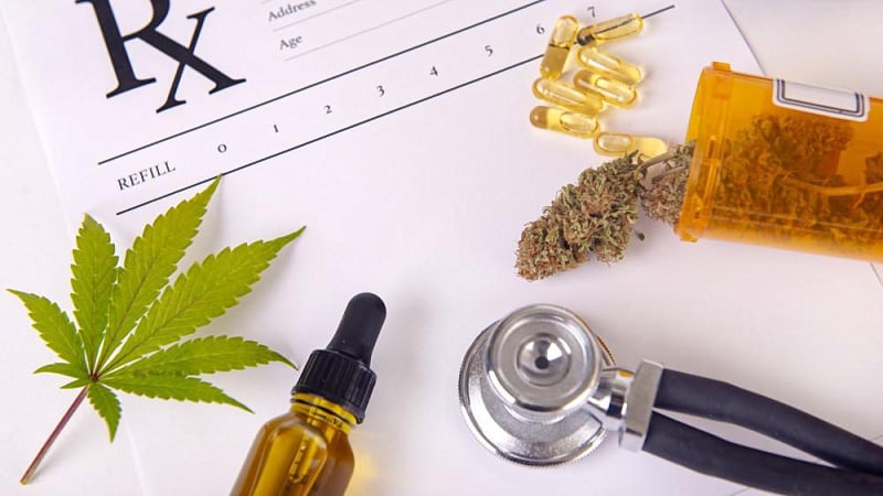 CBD oil, hemp leaf, stethoscope, capsultes and dried hemp flower bud place above a paper of medical prescription 