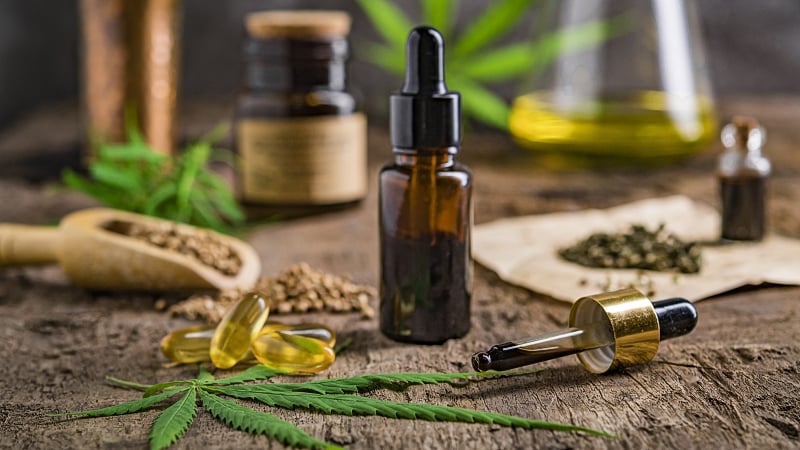 CBD oil extract and capsules with hemp seeds and leaves on wood