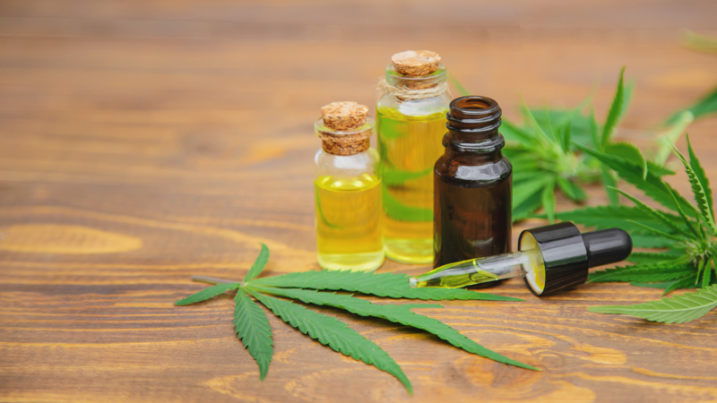 CBD Oil in Bottles with Hemp Leaves on a Wooden Surface