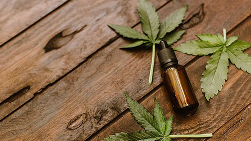 A bottle of CBD with hemp leaves on a wooden table.