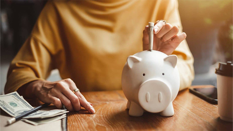 Woman putting dollar bill on a piggy bank